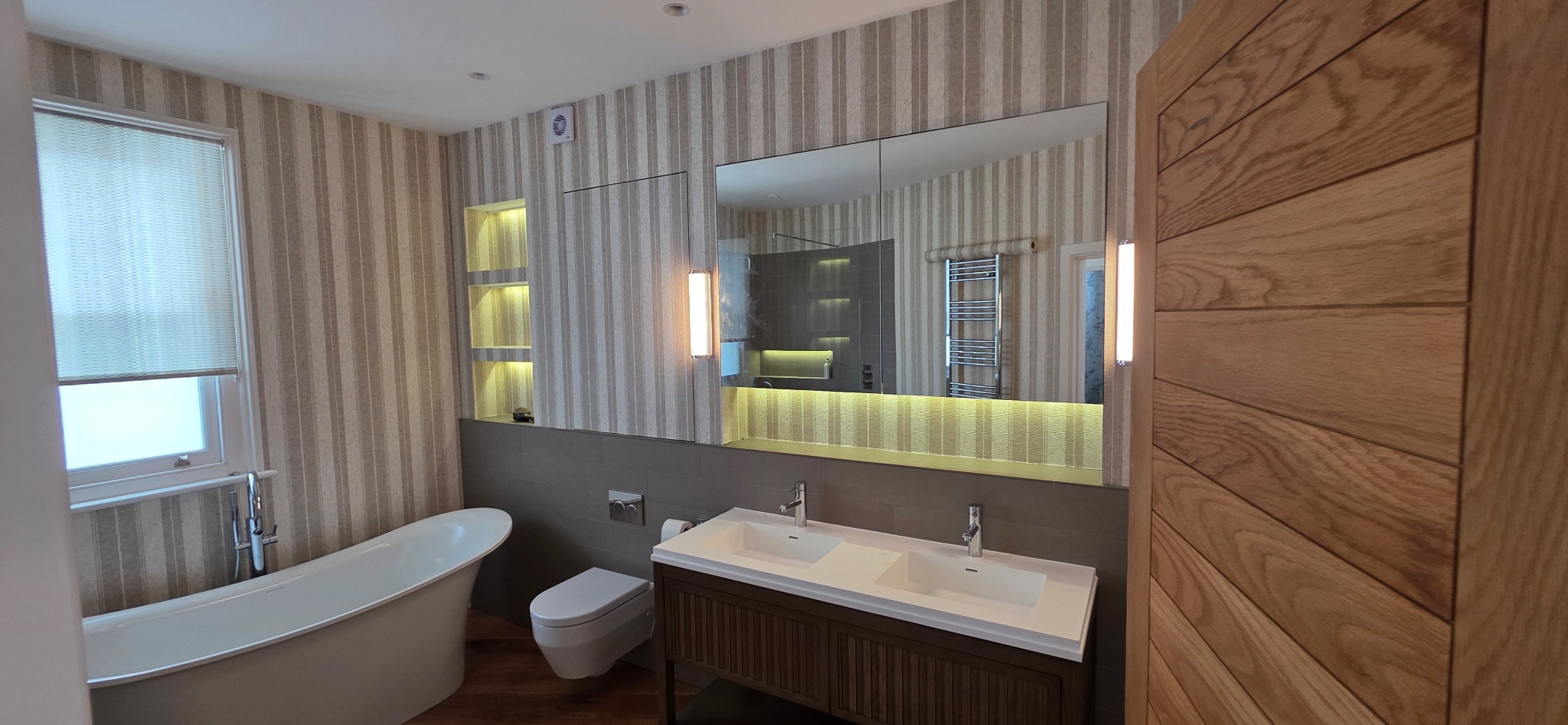 Bathroom with freestanding bath, double basin and illuminated mirror