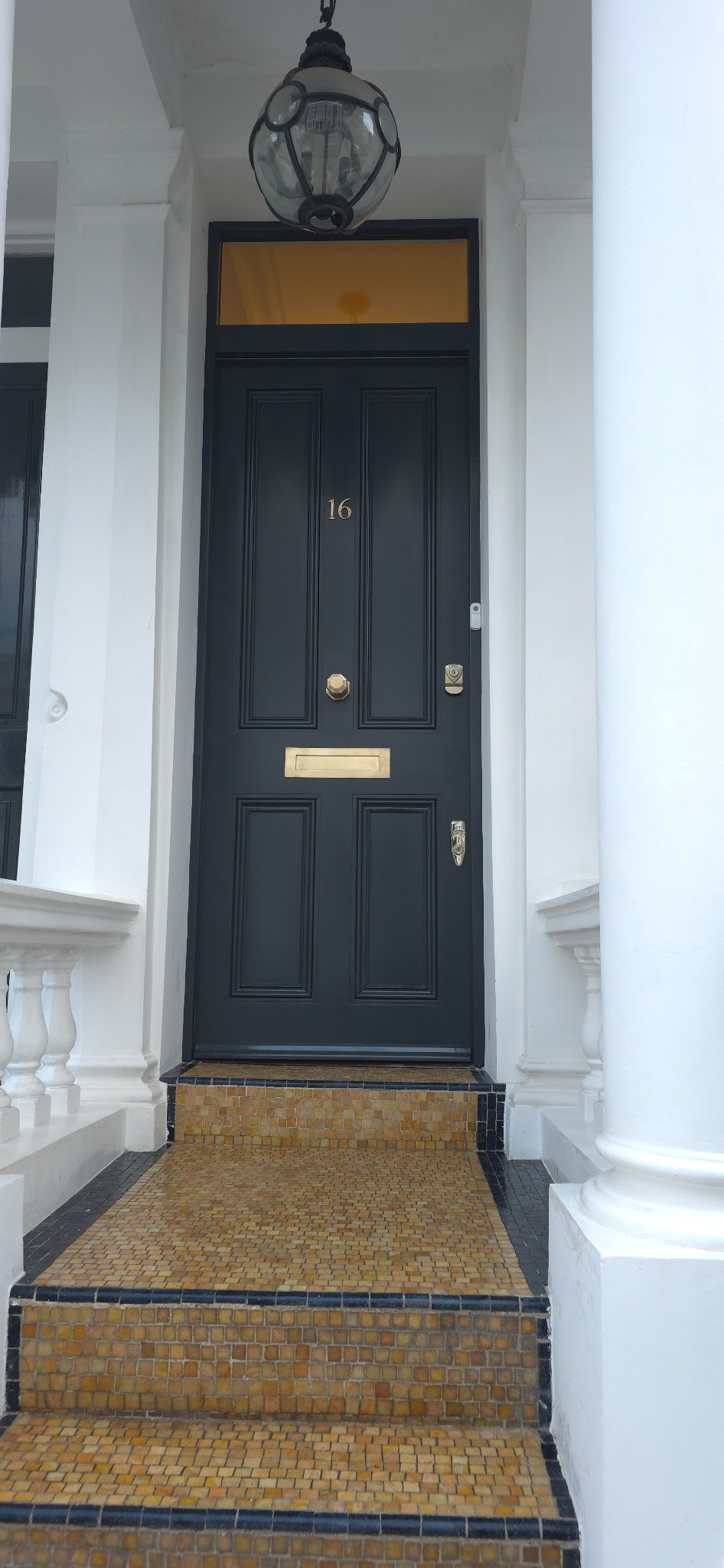 Restored dark front door with brass fittings and tiled entrance