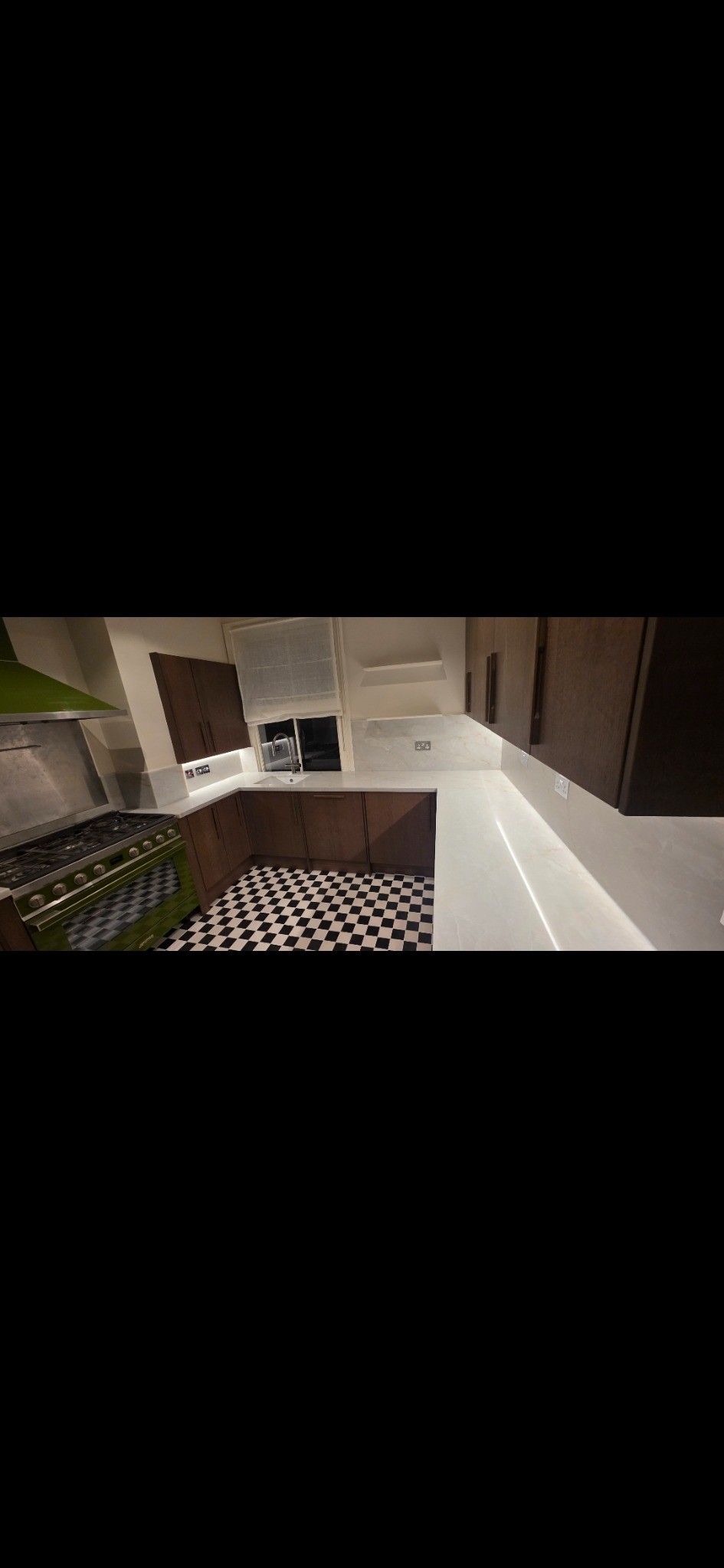 Finished kitchen with dark cabinetry, light worktops and tiled floor